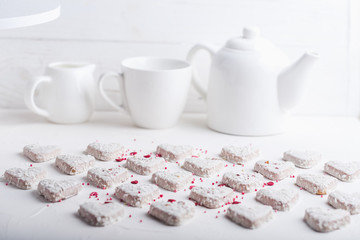  A pattern of Valentine's day white coconut heart shaped cookies on a white background  with red sprinkles. Copy space. Monochrome