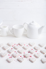  A pattern of Valentine's day white coconut heart shaped cookies on a white background  with red sprinkles. Copy space. Monochrome