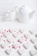 A pattern of Valentine's day white coconut heart shaped cookies on a white background  with red sprinkles. Copy space. Monochrome
