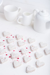  A pattern of Valentine's day white coconut heart shaped cookies on a white background  with red sprinkles. Copy space. Monochrome