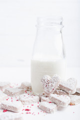  Valentine's day white coconut heart shaped cookies with red and pink heart sprinkles and milk bottle. Copy space