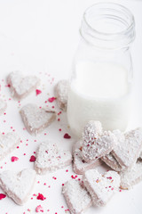  Valentine's day white coconut heart shaped cookies with red and pink heart sprinkles and milk bottle. Copy space