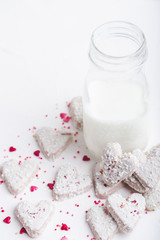  Valentine's day white coconut heart shaped cookies with red and pink heart sprinkles and milk bottle. Copy space