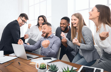 Happy businesspeople triumphing with raised fists in office