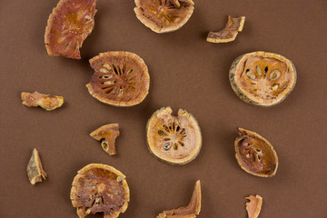 top view dried bael fruit (matum)  slices on a brown background