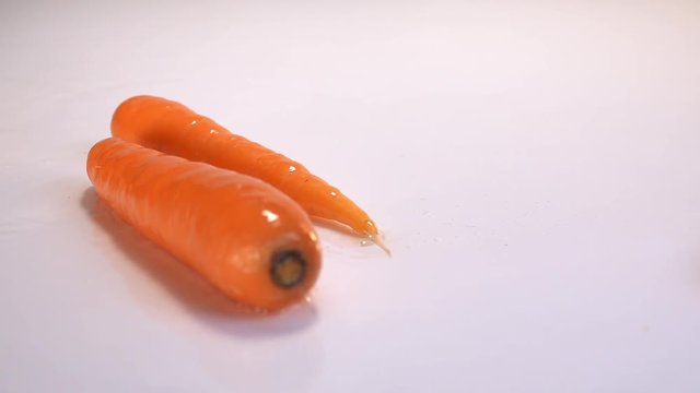 Carrot falling in water on white table in white background. Slow Motion 240 fps