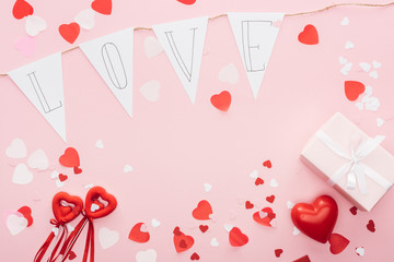 top view of valentines decorations and paper garland with 'love' lettering isolated on pink, st valentines day concept