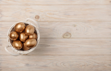 Happy easter! Easter decor and Easter eggs of golden color on a light wooden background.