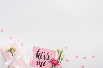 top view of flowers, gift box and card with 'kiss me' lettering isolated on white