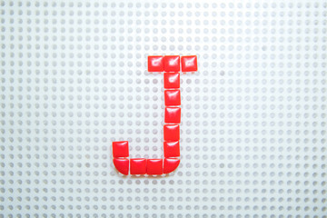 letter J created with children toys similar to pixels