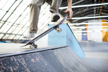 Agile parkour boy jumping in air over skateboard and edge of descent while training on stadium