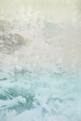 Frozen pattern on the window glass in the winter and tinted in blue, green and yellow