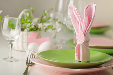 Happy easter. Decor and table setting of the Easter table - Branches of flowering spring tree, dishes of pink and green color.