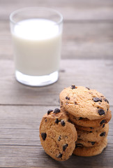 Glass of milk and chocolate cookies on grey background