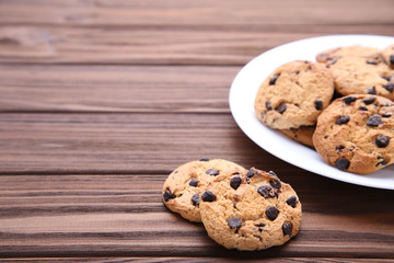 Chocolate chip cookies on plate on brown wooden background
