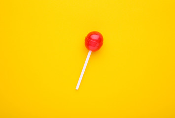 Sweet red lollipop on yellow background. sweet candy concept