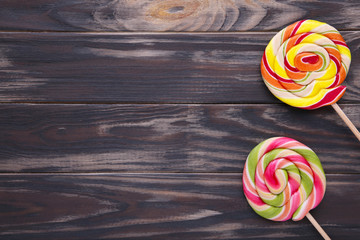 Colorful lollipops on a brown wooden background.
