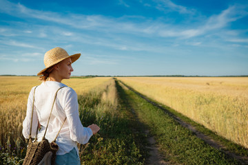 Naklejka na ściany i meble Beautiful girl in natural wheat field countryside holiday ecotourism, rural