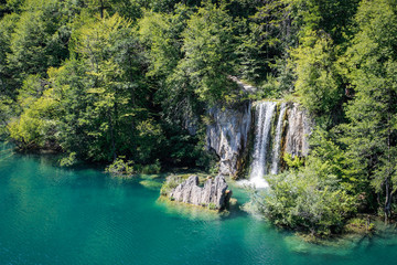 Fototapeta na wymiar The main natural landmark of Croatia is the Plitvice Lakes with cascades of waterfalls. Emerald clear cold water on the background of rocks, plants and trees.