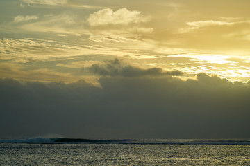 Obraz premium A perfect wave breaks over the reef in black river on the island of Mauritius. A storm from out to sea created some bog swell amazing light over the ocean.