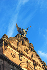 angel with a golden trombone on top of a historic opera house