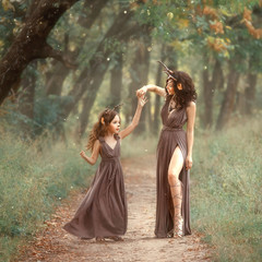 fairy mother deer on path spinning her daughter on a forest trail, wearing long brown dresses,...
