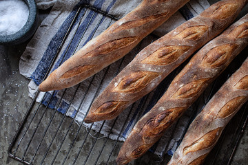 Fresh artisanal bread baguettes on linen towel. Traditional french baguettes made from wheat flour, top view.