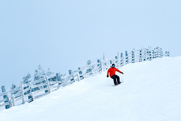 Young man snowboarder running down the slope. Winter sport and recreation, leisure outdoor...