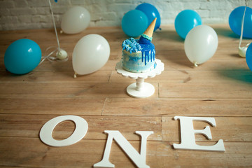 Decorations for one year birthday with balloons, festive cake and inscriptions on floor.