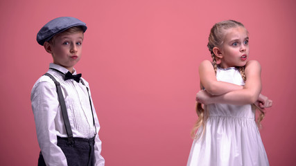 Little male looking into camera shocked with girlfriends complaint, kids quarrel