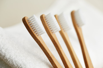 Four bamboo toothbrushes on white towel, close up