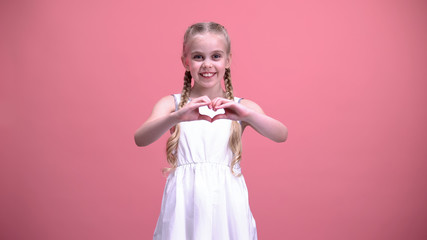 Cute little girl with braids showing heart gesture, charity, children adoption