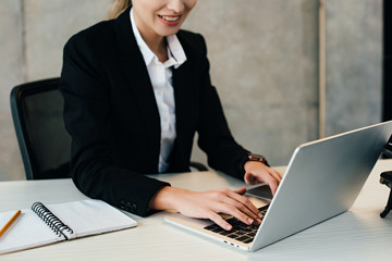 Cropped view of smiling businesswoman using laptop in office