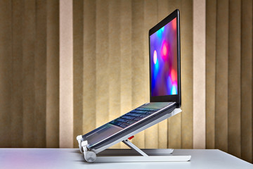 Standing laptop holder set up with notebook on desk.