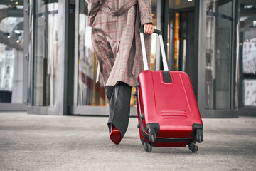 Close up of woman carrying suitcase at the airport terminal
