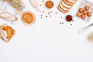 Homemade breads or bun, croissant and bakery ingredients, flour, almond nuts, hazelnuts, eggs on white background, Bakery background frame, Cooking breakfast concept. Flat lay, Top view and copy space