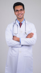 Happy young handsome Indian man doctor with arms crossed