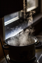 the man stirs the soup in the pan from which steam comes