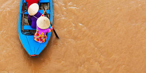 Vietnamese old woman on traditional boat in Mekong river delta
