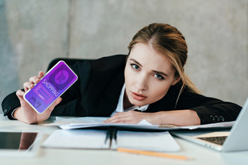 selective focus of businesswoman at work-table showing screen of smartphone with shopping