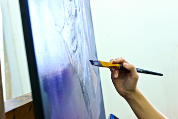 Hand with a brush next to the art canvas