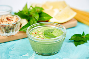 Homemade pesto sauce in glass jar with ingredients.