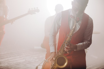 young attractive musician plays tenor saxophone on stage. close up photo