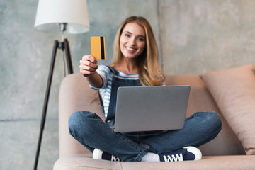 beautiful woman with laptop smiling and showing credit card