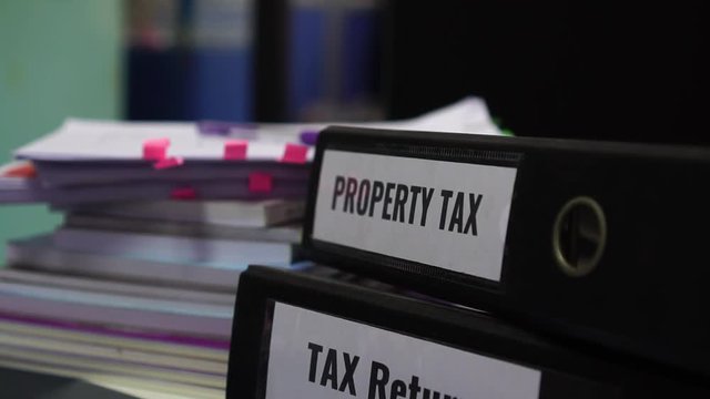 Property tax and tax return word on folders stack with label black binder on paperwork documents summary report in busy offices. HR-human resources business bookkeeping accountancy Document Concept