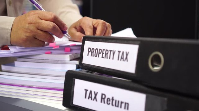 Tax return / property tax / Tax income word on folders stack label black binder on paperwork documents summary report in busy offices by manager checking. HR-human resources business accountancy ideas
