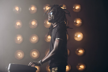 African guy with dreadlocks enjoying playing synthesizer. close up side view photo.