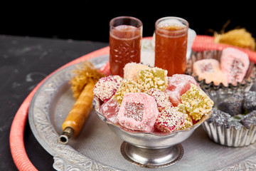Set of various Turkish delight in bowl on metal tray near hookah tube