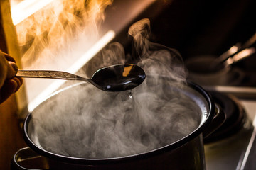 the man stirs the soup in the pan from which steam comes - 245921099