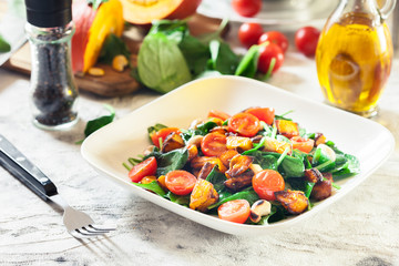 Roasted pumpkin salad with spinach, tomatoes and nuts